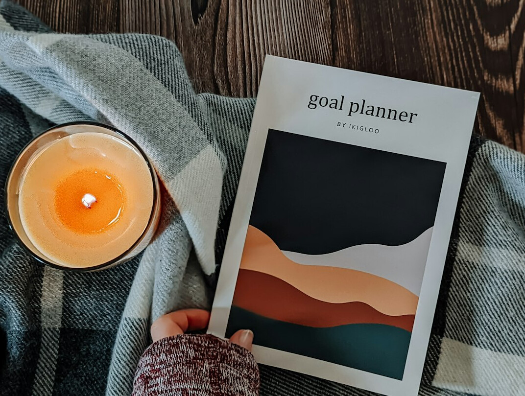 Brazilian woman writing goals in a planner at a wooden desk